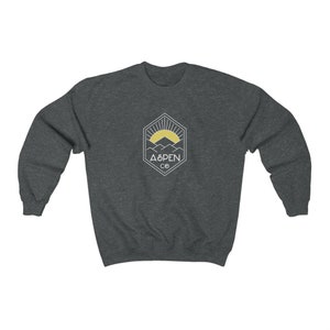 May include: A dark gray sweatshirt with a white graphic of a mountain range and a sun with the text "ASPEN CO" in a hexagon.