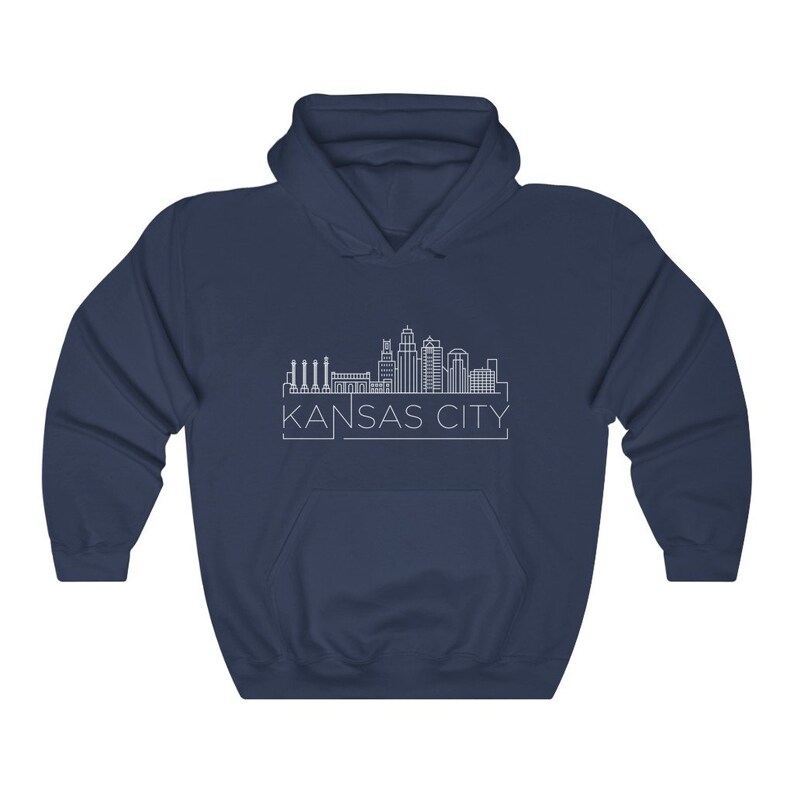 Może przedstawiać: Granatowa bluza z kapturem z białym rysunkiem linii horyzontu Kansas City. Nazwa miasta jest wydrukowana na dole na biało. Bluza ma przednią kieszeń i kaptur ze sznurkiem.