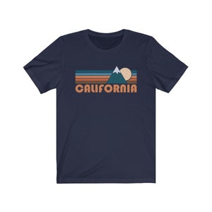 May include: A navy blue t-shirt with a retro-style graphic of a mountain range, sun, and the word "CALIFORNIA" in orange.