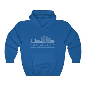 Może przedstawiać: Kr&oacute;lewska niebieska bluza z kapturem z białym rysunkiem linii horyzontu Kansas City. Tekst "KANSAS CITY" jest wydrukowany poniżej w kroju bezszeryfowym. Bluza ma przednią kieszeń i kaptur ze sznurkiem.