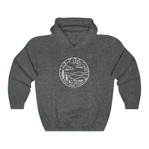 May include: A dark grey hooded sweatshirt with a white outline of a circle containing the words "North Carolina" and a landscape scene with trees, mountains, and clouds. The text "Esse Quam Videri" is written below the landscape.