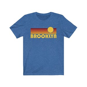 May include: A blue t-shirt with a retro sunset graphic and the word "BROOKLYN" in yellow letters.