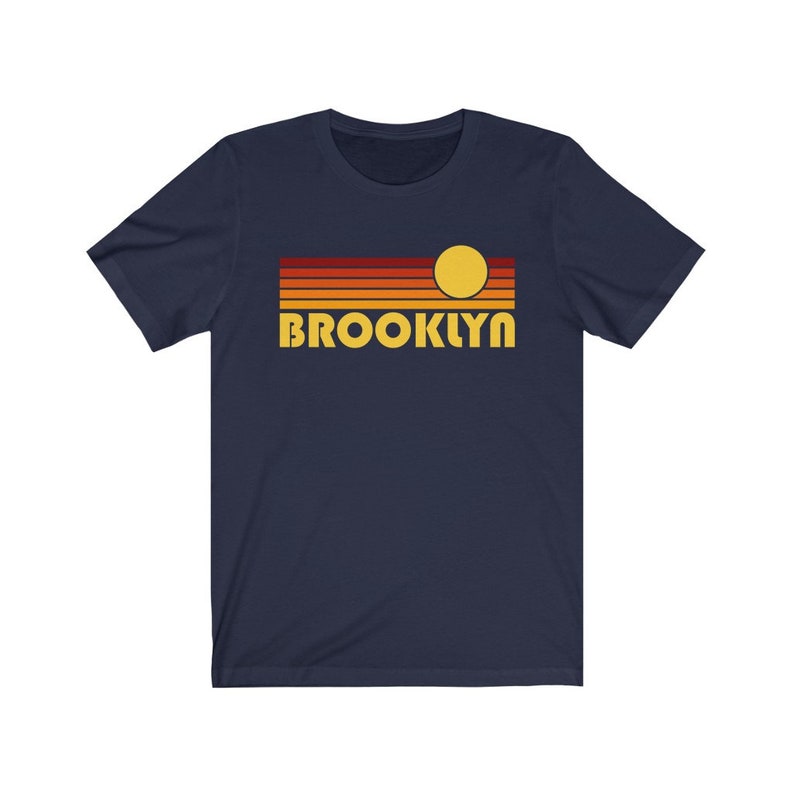 May include: Navy blue t-shirt with a retro sunset graphic and the word "BROOKLYN" in yellow letters.