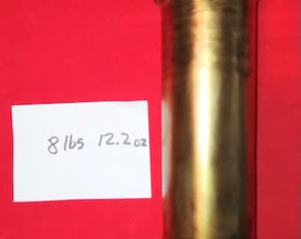 May include: A cylindrical brass object with a rounded top and bottom, featuring a small loop at the top. The object is approximately 8 lbs 12.2 oz. The background is a solid red.