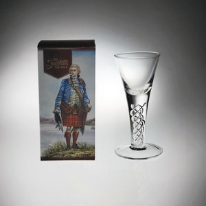May include: A clear glass with a twisted stem and a wide, shallow bowl. The glass is packaged in a box with a picture of a man in a kilt and the text "The Jacobite Glass".