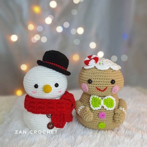 以下が含まれることがあります： クリスマスの飾り付けをした、かぎ針編みで作られた雪だるまといちごの男性。雪だるまは白で、黒いシルクハットと赤いマフラーをしています。いちごの男性は茶色で、白いアイシングのシルクハットと緑色の蝶ネクタイをしています。 ZAN CROCHETは、フィギュアの下の白い表面に書かれています。