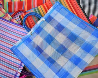 Könnte beinhalten: Eine Sammlung farbenfroher, gewebter Tragetaschen. Die Taschen weisen verschiedene Muster auf, darunter Streifen und ein blau-weißes Karomuster. Einige Taschen haben blaue Griffe.