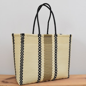 May include: A woven tote bag with black and brown stripes. The bag has black handles and is made of a natural material.