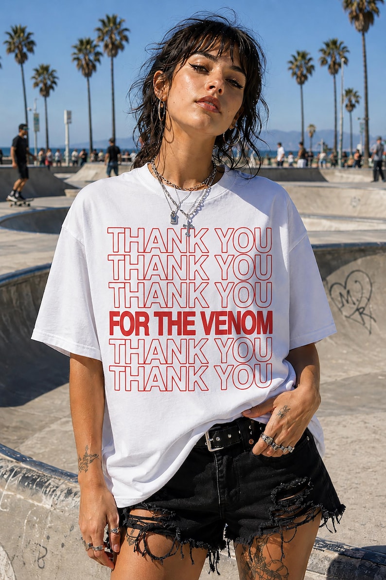 May include: White t-shirt with red text that reads "THANK YOU THANK YOU THANK YOU FOR THE VENOM THANK YOU THANK YOU THANK YOU." The shirt is worn by a person in black shorts and a black belt.