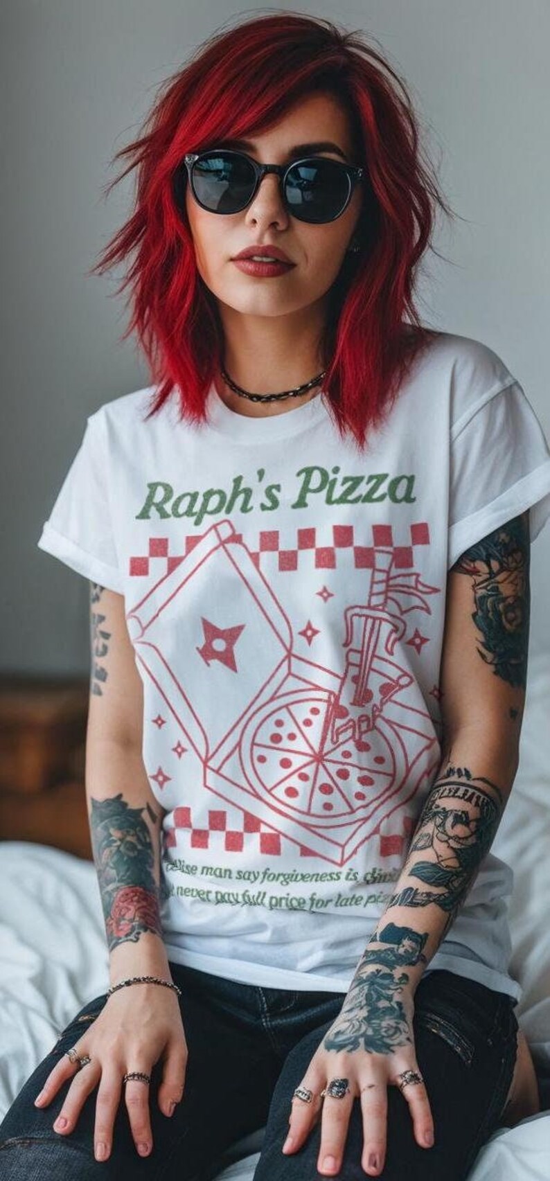 May include: A woman with red hair and tattoos is wearing a white t-shirt with a red and white pizza box graphic and the text "Raph's Pizza". The shirt also has the text "wise man say forgiveness is cheap, never pay full price for late pizza".