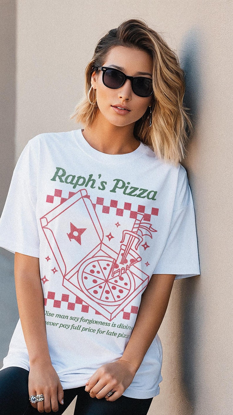 May include: White t-shirt with a red and white illustration of a pizza box and a slice of pizza. The text "Raph's Pizza" is printed in green on the shirt. The text "Wise man say forgiveness is divine, never pay full price for late pizza" is printed in green at the bottom of the shirt.