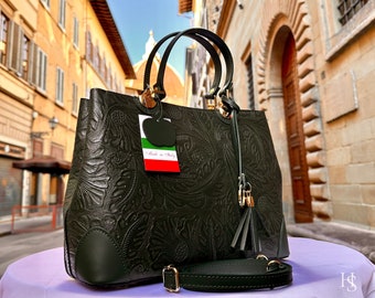 May include: Dark green leather handbag with a floral embossed design. Features include top handles, a detachable shoulder strap, and a decorative tassel. The bag has a tag that says "Made in Italy".