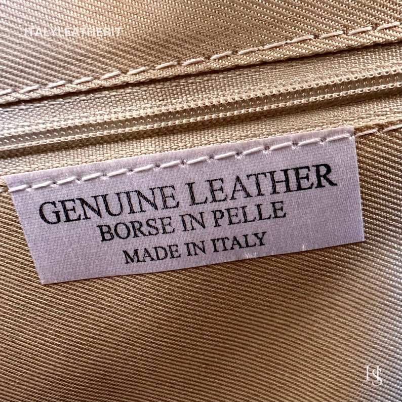 May include: Close-up of a white label with black text that reads "GENUINE LEATHER BORSE IN PELLE MADE IN ITALY".