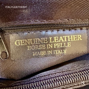 K&ouml;nnte beinhalten: Nahaufnahme einer braunen Lederhandtasche mit einem goldenen Etikett mit der Aufschrift "GENUINE LEATHER BORSE IN PELLE MADE IN ITALY".