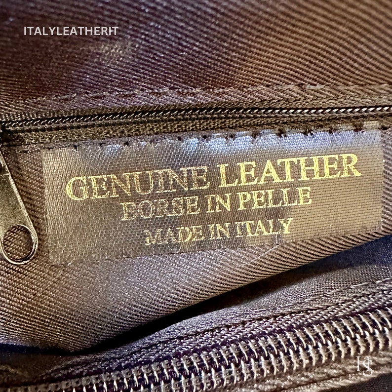 K&ouml;nnte beinhalten: Nahaufnahme einer braunen Lederhandtasche mit einem goldenen Etikett mit der Aufschrift "GENUINE LEATHER BORSE IN PELLE MADE IN ITALY".