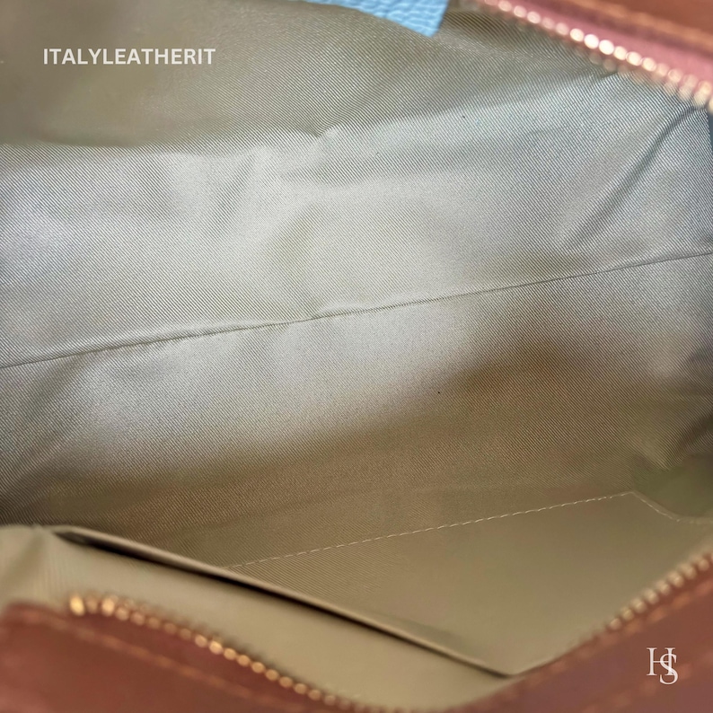 Puede incluir: Vista interior de un bolso de mano de cuero marr&oacute;n con forro de tela beige claro. El bolso tiene un cierre de cremallera y un peque&ntilde;o bolsillo. El texto "ITALYLEATHERIT" es visible.