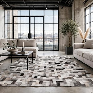 May include: A rectangular area rug featuring a geometric patchwork pattern composed of small, interlocking rectangular tiles in varying shades of black, white, gray, and beige, creating a textured, multi-tonal surface across the floor.