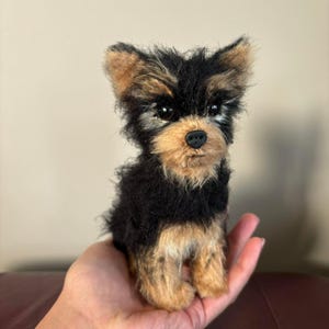 May include: A small black and brown Yorkshire Terrier dog plush toy with a black nose and brown eyes.
