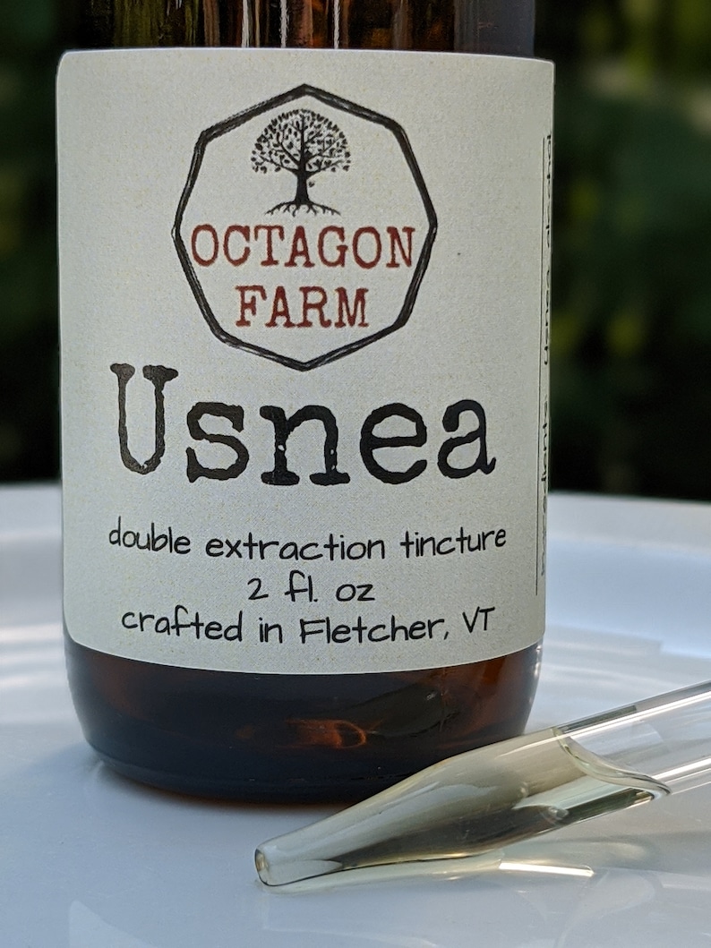 K&ouml;nnte beinhalten: Eine braune Glasflasche mit einem wei&szlig;en Etikett, auf dem "OCTAGON FARM Usnea double extraction tincture 2 fl. oz crafted in Fletcher, VT" steht.