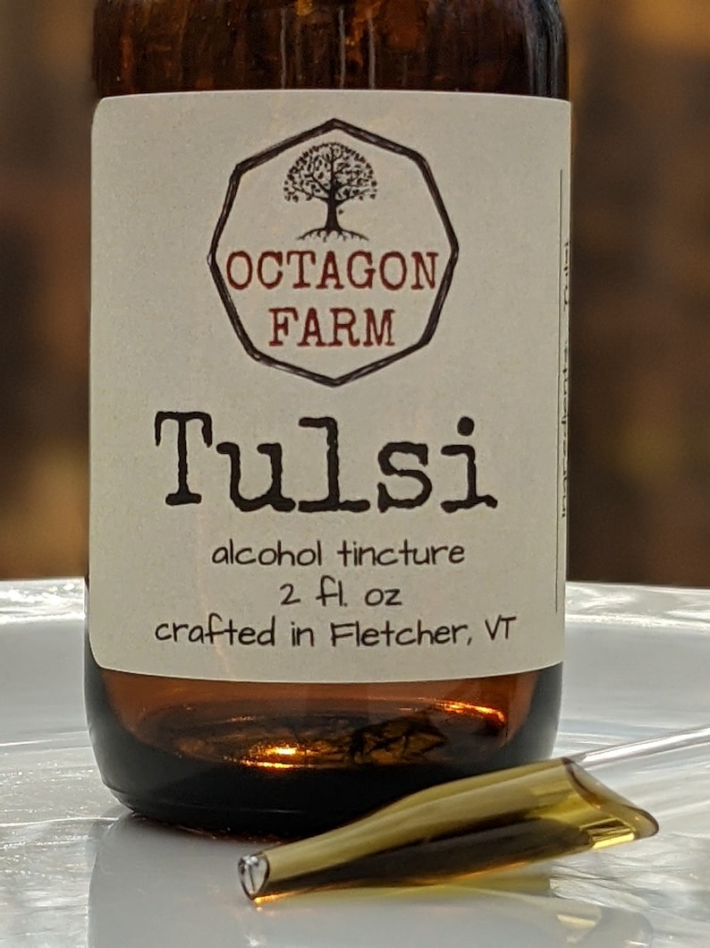 May include: A brown glass bottle with a white label that reads "Octagon Farm Tulsi alcohol tincture 2 fl oz crafted in Fletcher, VT". The label features a black and white illustration of a tree in an octagon.