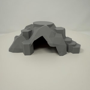 Könnte beinhalten: Graue, 3D-gedruckte Höhlenstruktur mit einer kreisförmigen Plattform oben und einer zentralen Öffnung. Das Design weist geometrische Formen und Stufen auf und schafft eine Miniaturlandschaft.