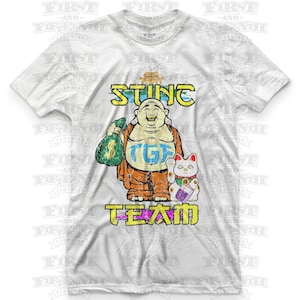 May include: White t-shirt with a distressed graphic of a smiling Buddha holding a bag of money and a lucky cat. The text "STING" is above the Buddha and "TGIF TEAM" is below.