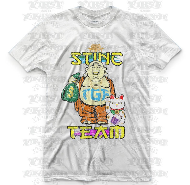 May include: White t-shirt with a distressed graphic of a smiling Buddha holding a bag of money and a lucky cat. The text "STING" is above the Buddha and "TGIF TEAM" is below.