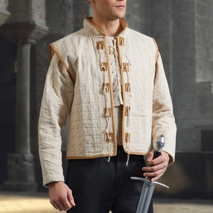 May include: A white quilted vest with brown leather accents and a lace-up front. The vest has a stand-up collar and long sleeves. A person is holding a silver sword.