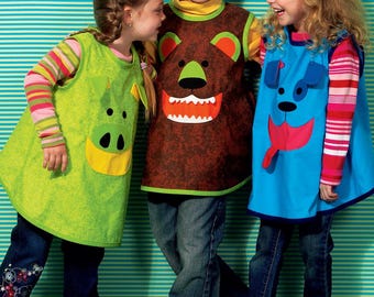 May include: Three children wearing animal-themed aprons. One child wears a green apron with a pig face, another a brown bear, and the third a blue dog. They are all wearing jeans and sneakers. The background is a teal and white striped pattern.