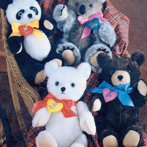 May include: Four plush stuffed animals, a panda, a koala, a white teddy bear, and a brown teddy bear, are sitting in a wicker basket lined with a red and black plaid blanket. Each animal is wearing a ribbon with a heart-shaped charm.