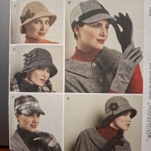 May include: A sewing pattern envelope featuring five hat designs labeled A through E. Designs include a tan hat with a bow, a grey paneled cap, a dark grey textured bucket hat with triple bows, a plaid cap, and a grey bucket hat with floral accents.