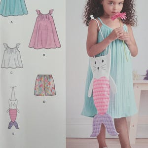 May include: A young girl wearing a light blue dress and holding a pink flower. She carries a white purse shaped like a cat with a mermaid tail. The image also shows illustrations of children's clothing, including dresses and shorts.