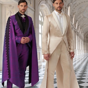 May include: Two men wearing formal attire. One man is wearing a purple suit with a black cape and a black bow tie. The other man is wearing a beige suit with a white shirt and a white bow tie. Both men are standing in a grand hall with marble floors and ornate ceilings.
