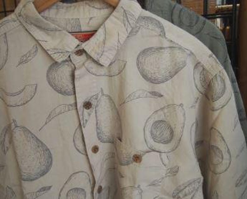 May include: A white button-down shirt with a black and white avocado print. The shirt has a pocket on the left side.
