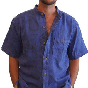 May include: A blue short-sleeved button-down shirt with a black avocado print. The shirt has a mandarin collar and a chest pocket.