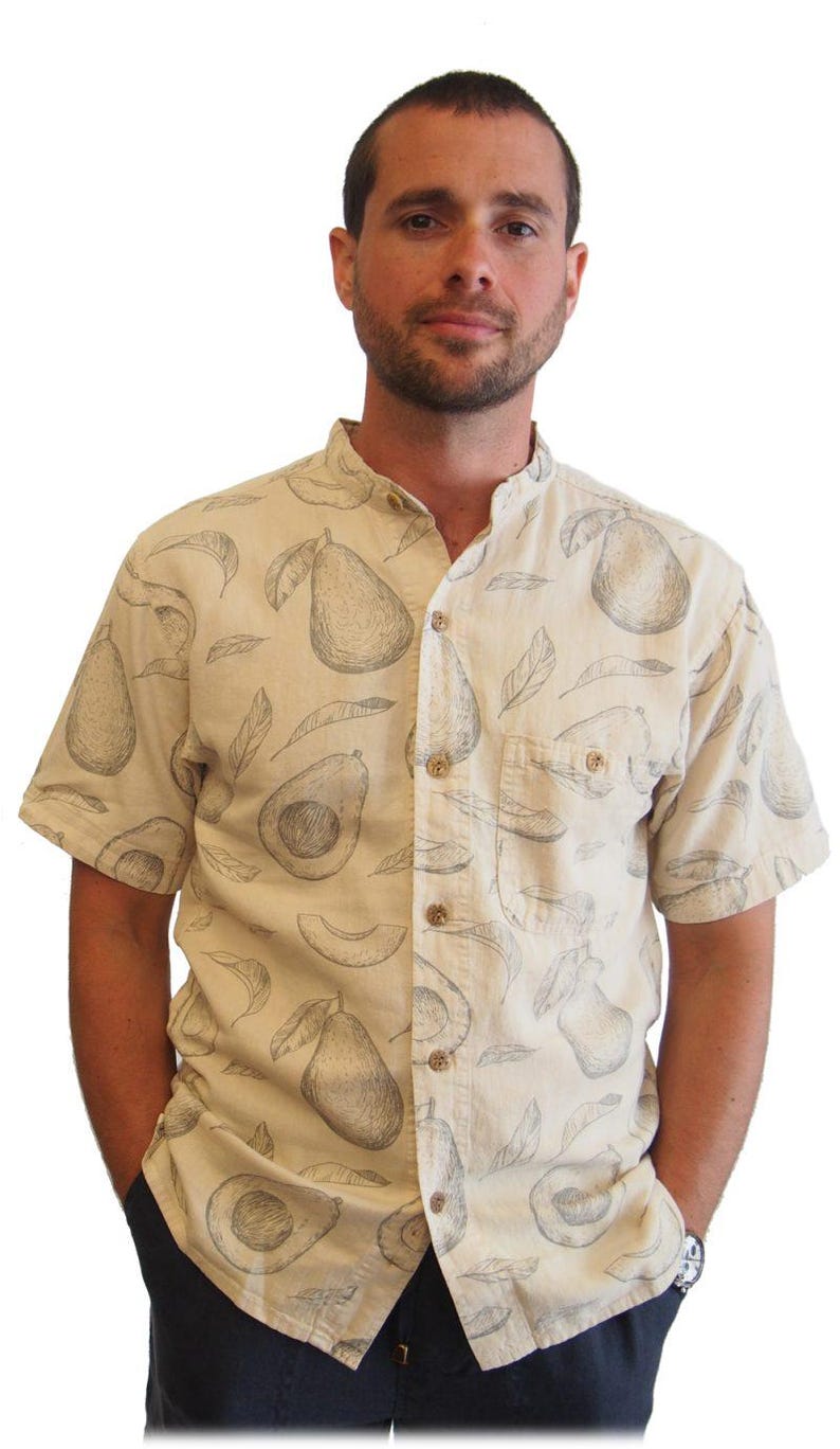 May include: A beige short-sleeved button-up shirt with a mandarin collar and a pattern of black and white avocado drawings.