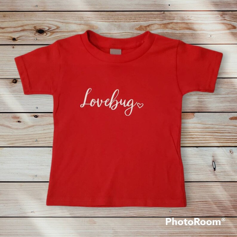 May include: Red short-sleeved t-shirt with the text "Lovebug" in white cursive lettering and a small white heart.