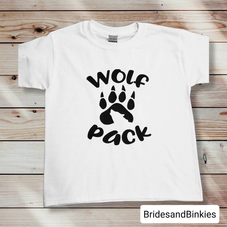 Puede incluir: Camiseta blanca con una huella de pata de lobo negra y el texto "Wolf Pack" impreso en la parte delantera.