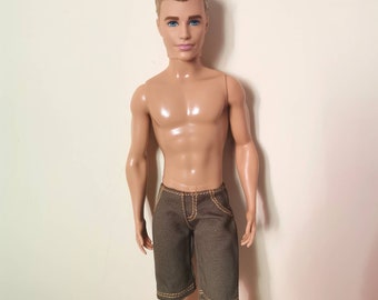 May include: A plastic doll with short blond hair and blue eyes, wearing brown denim shorts.