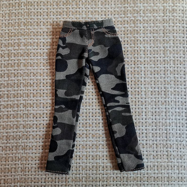 May include: Camouflage print pants with a brown and green color scheme. The pants have a straight leg and a zipper fly.