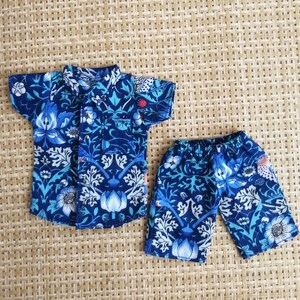 May include: A blue and white patterned short-sleeved shirt and matching shorts. The fabric features a floral design with blue, white, and green accents.