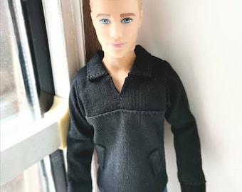 May include: A doll with blond hair wearing a black long-sleeved shirt and blue jeans.