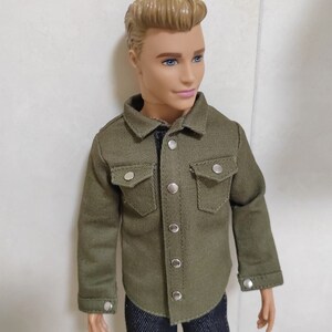 Pode incluir: Uma camisa verde de bot&otilde;es com mangas compridas e dois bolsos no peito. A camisa tem bot&otilde;es prateados e &eacute; feita de um tecido macio e texturizado.