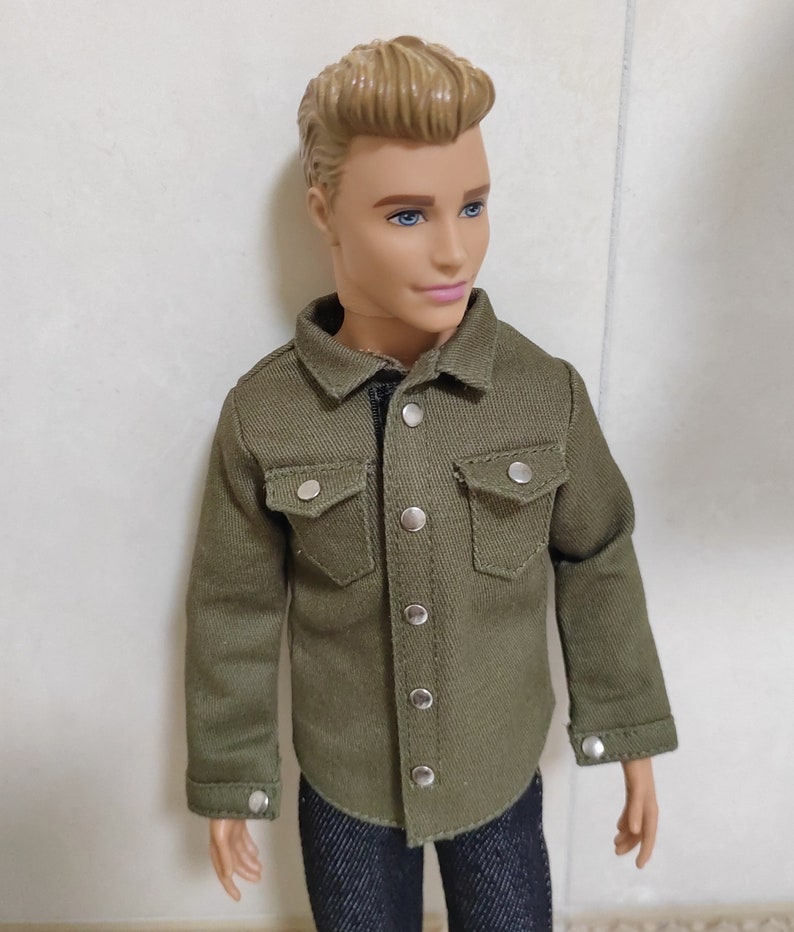Pode incluir: Uma camisa verde de bot&otilde;es com mangas compridas e dois bolsos no peito. A camisa tem bot&otilde;es prateados e &eacute; feita de um tecido macio e texturizado.