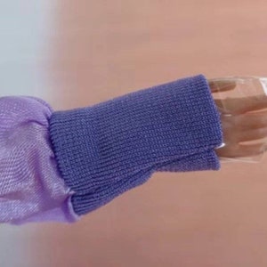 May include: A purple and lavender long-sleeved shirt with a ribbed knit cuff. The cuff is folded back to reveal a clear plastic sleeve.