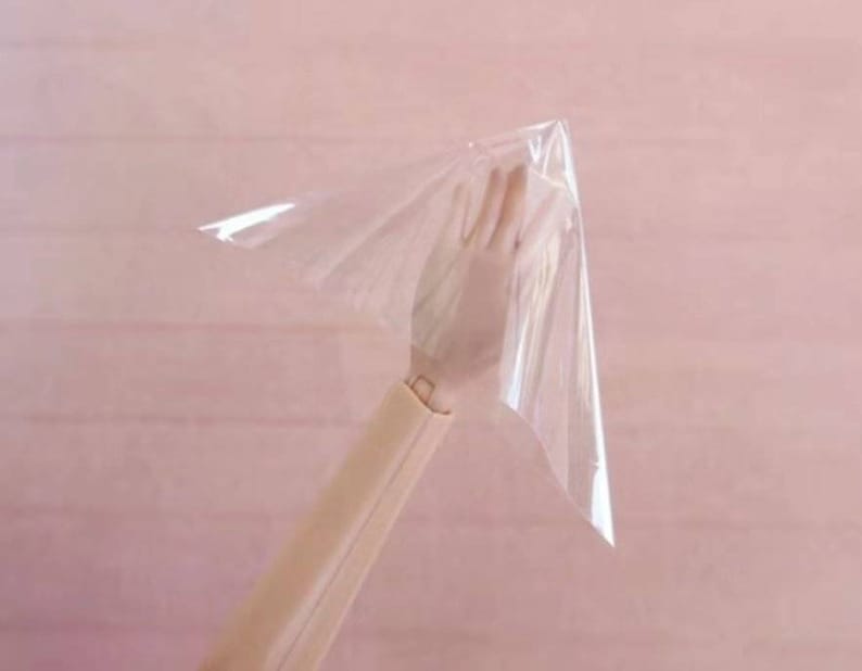 May include: A clear plastic sheet held up by a hand, the sheet is shaped like a cone.