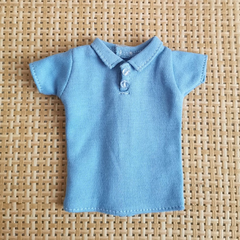 May include: A light blue short-sleeved polo shirt with a button closure. The shirt is made of a soft, comfortable fabric and has a classic, casual style.