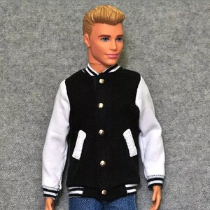 May include: A black and white varsity jacket with gold buttons. The jacket has white sleeves with black stripes at the cuffs and bottom hem.