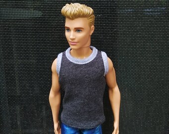 May include: A doll with short, blond hair wearing a gray sleeveless shirt and blue jeans.