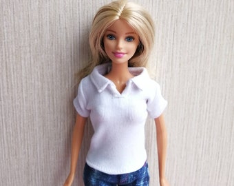 May include: A blonde doll wearing a white collared shirt and blue jeans. The doll has blue eyes and pink lips.